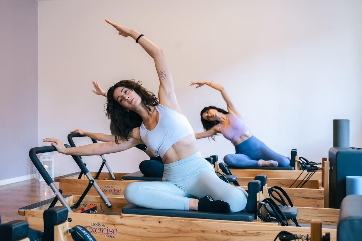 due ragazze praticano l'esercizio di pilates mermaid su reformer